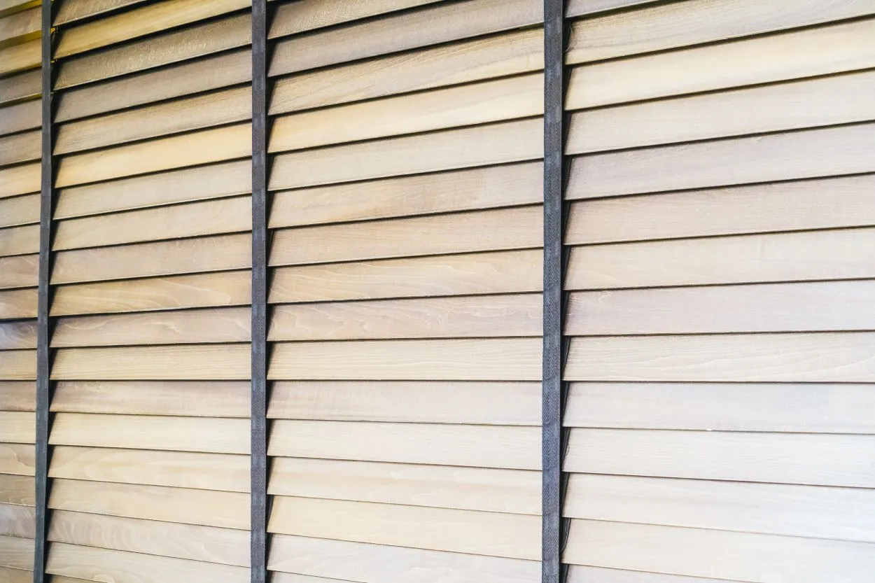 Bardage en bois à claire-voie, installé à l’horizontale. Les lames de bois sont légèrement espacées et posées en quinconce. Les montants verticaux sombres servent de structure porteuse et permettent de fixer solidement les lames.