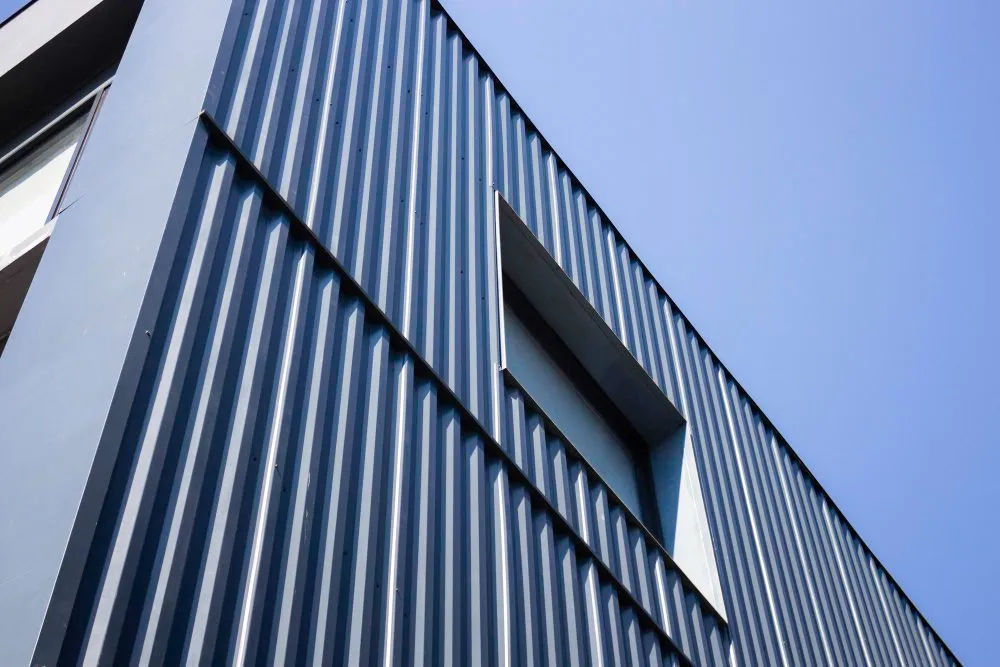 Façade de bâtiment habillée d’un bardage métallique en zinc gris sous un ciel bleu