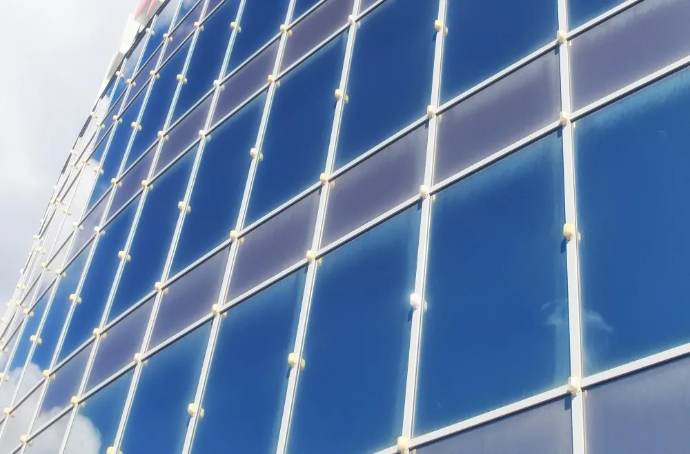 Façade vitrée moderne avec reflets du ciel et structure métallique en grille