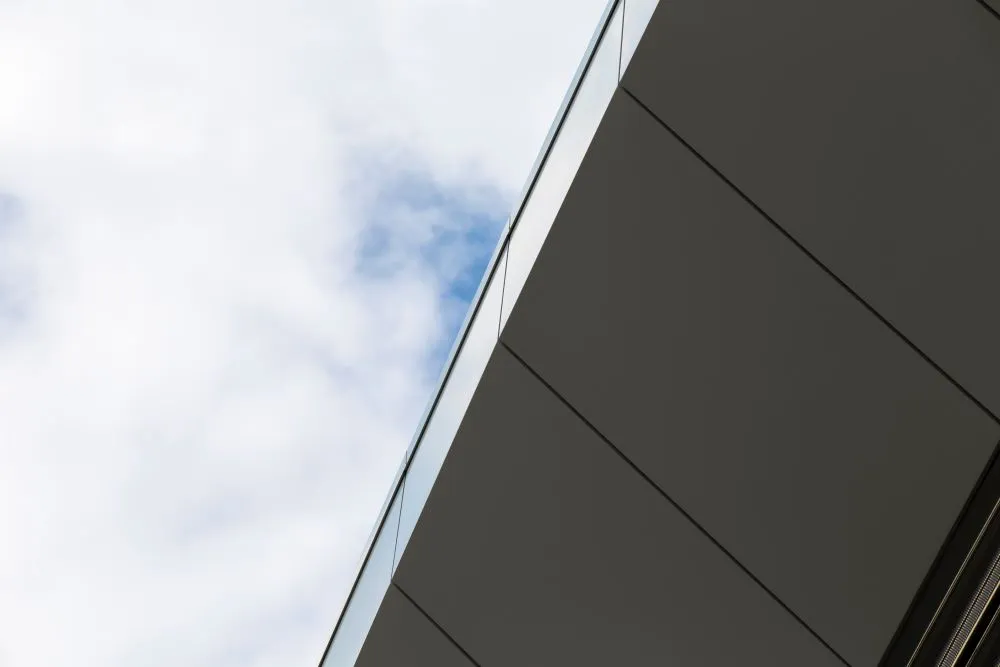 Vue rapprochée d’une façade contemporaine composée de panneaux plans, illustrant l’usage du panneau composite aluminium extérieur en bardage rapporté.