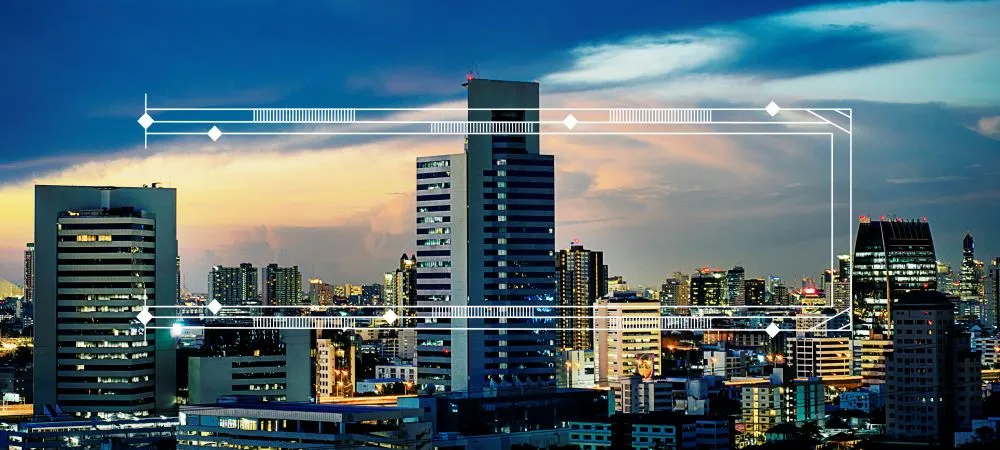 Skyline de bâtiments contemporains sous surveillance numérique, illustrant les capteurs et systèmes automatisés des façades connectées.